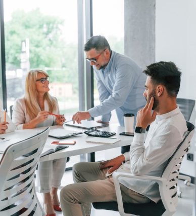 Talking and working on the project together. Group of professional business people is in the office.